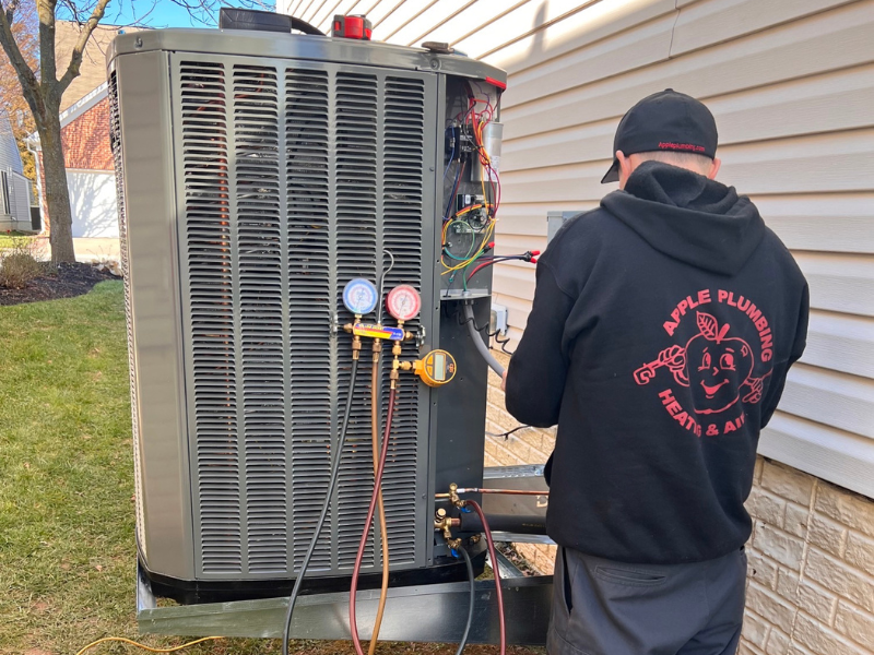 Apple HVAC technician servicing an outdoor AC unit.