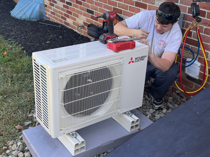 Apple HVAC technician installing mini split outdoor unit in Manchester, MD