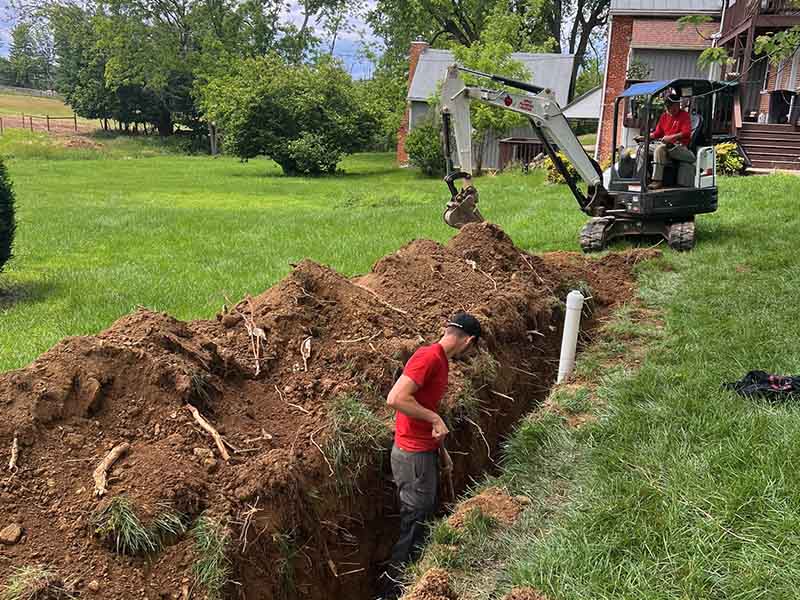 Apple Plumbing, Heating, & Air plumber digging out sewer line.